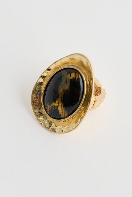Gold ring with a black gemstone on a light gray background
