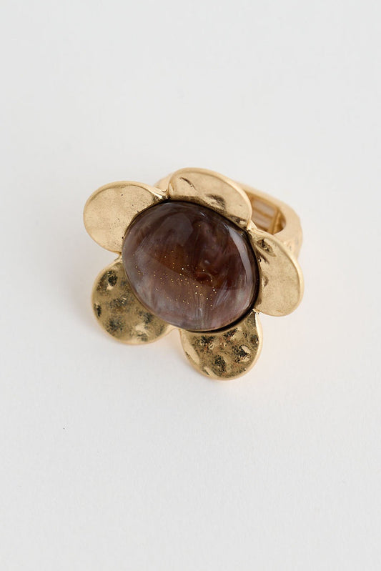 Gold earring with a brown gemstone on a light gray background