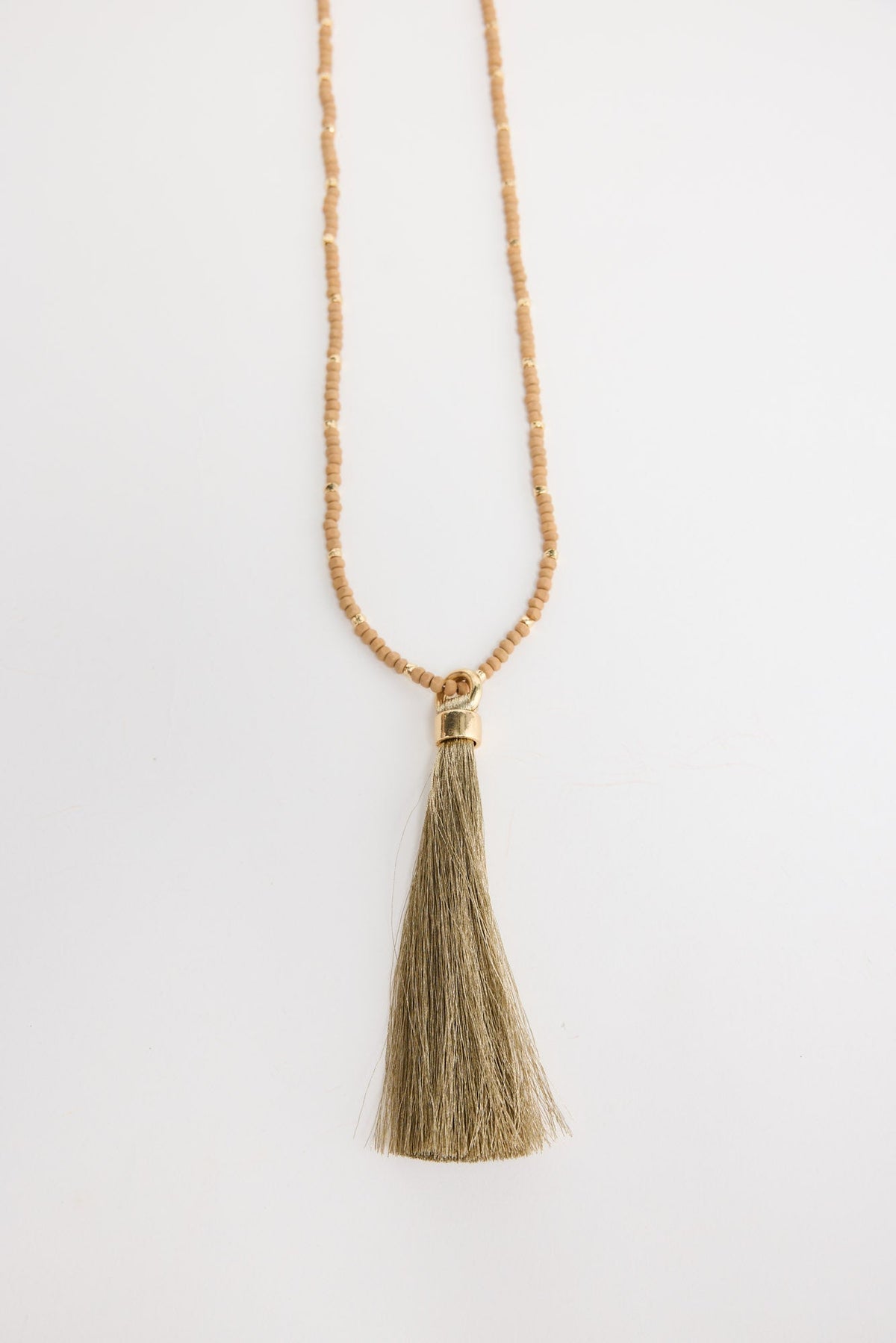 Long neutral taupe seed bead necklace with gold-tone spacer beads and a large olive-gold silk tassel pendant with a gold cap, shown flat on a white background