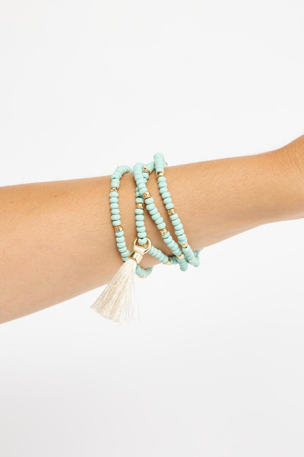 Mckenzie Bracelet worn on the wrist, showing the multi-wrap blue beaded strands and cream tassel charm