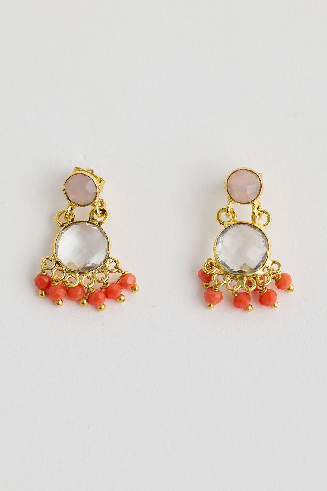 Pair of gold earrings with pink and orange beads on a light gray background