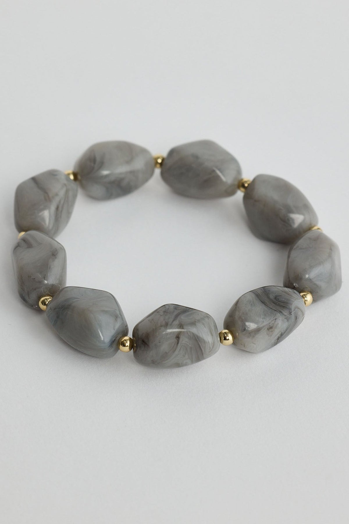 Gray beaded bracelet with gold accents on a light gray background