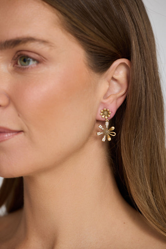 Close-up of a woman wearing gold earrings with a neutral background