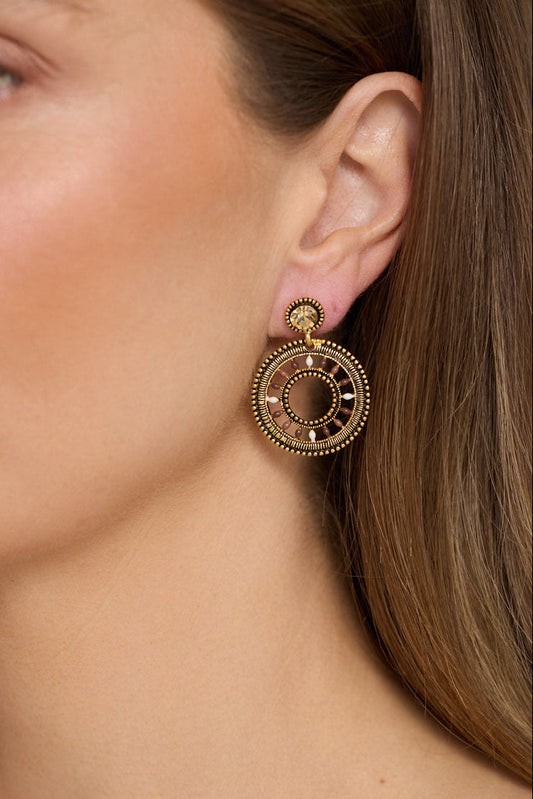 Model wearing Eclipse Earrings in gold with detailed textured finish, side profile view on neutral background