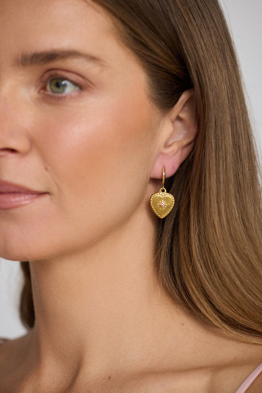 Model wearing Aura Earrings in gold with delicate stone detailing, side profile view on neutral background