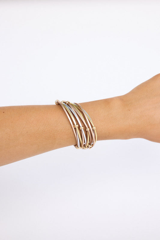 Model wearing Ainsley Bracelet in metallic with fine metallic cords, on-wrist view on neutral background