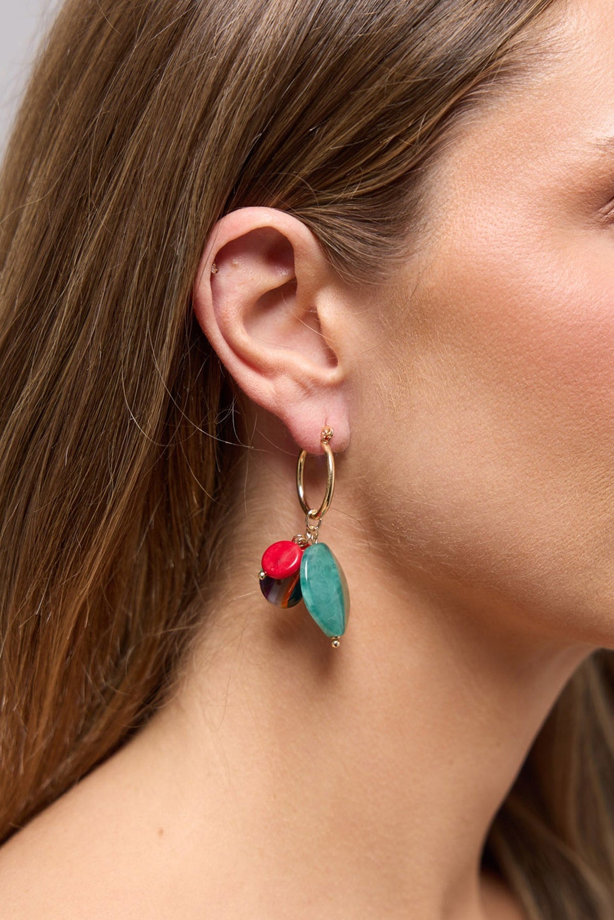 Close-up of the Elias Earrings in Green worn on the ear, showing the mixed resin charm cluster