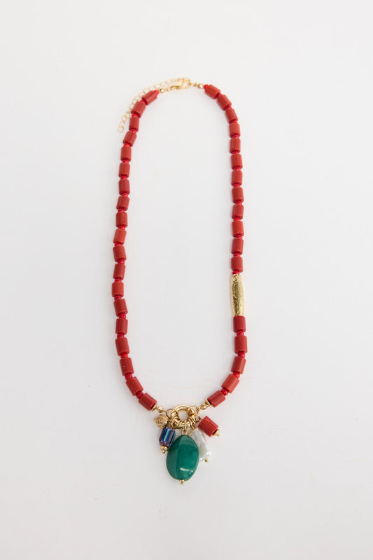 Elias beaded necklace laid flat, showing the red bead strand with a gold accent tube and a charm cluster of green stone, pearl and multicolour beads