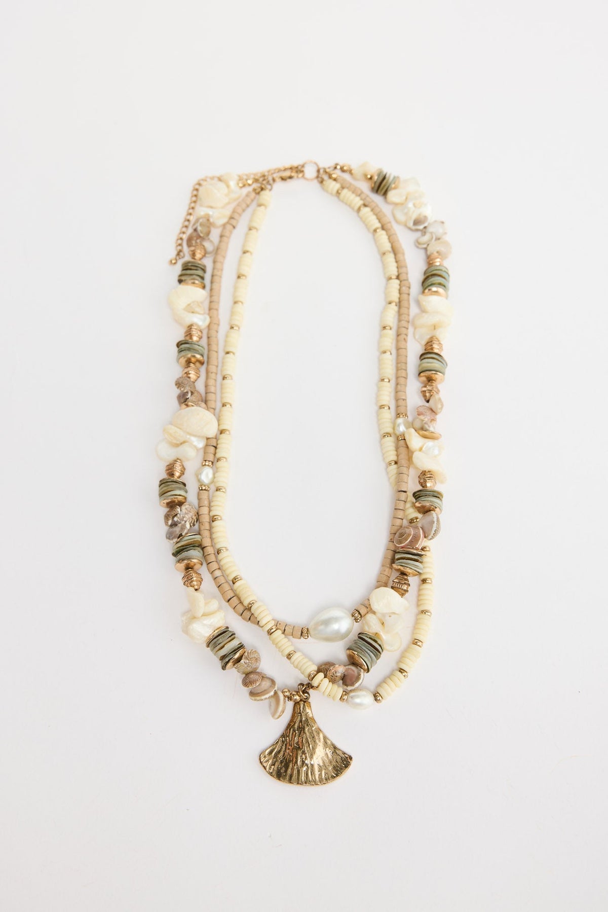 Otis multi-strand necklace laid flat, showing cream and tan disc beads, shell chip accents, pearls and a gold-tone fan pendant