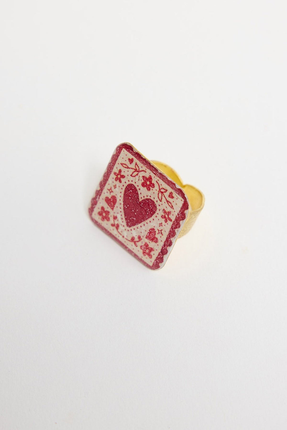 Love Sick Ring in Red, showing the square heart-print charm face on a gold-tone adjustable band