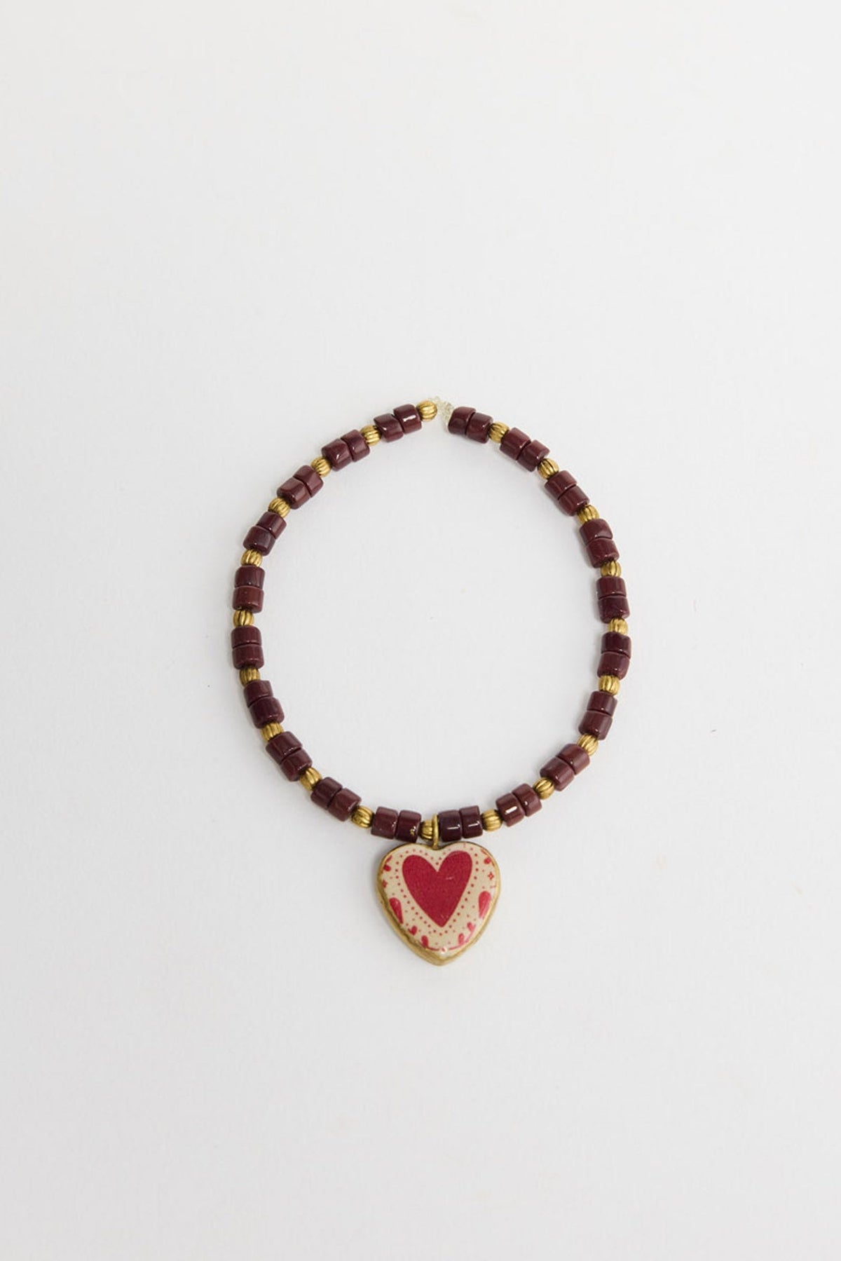Love Sick stretch Bracelet in Red laid flat, showing the burgundy beads, gold-tone spacers and heart-print charm