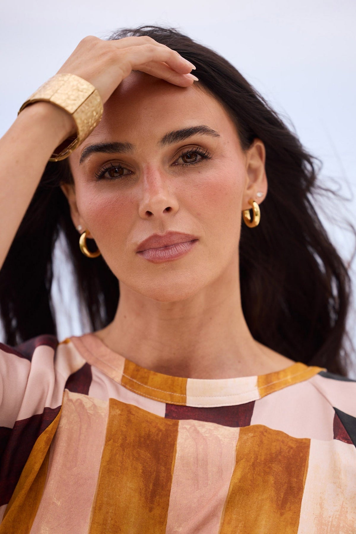 Model wearing Thick Hoops L in Gold paired with a printed top and gold cuff, campaign shot.
