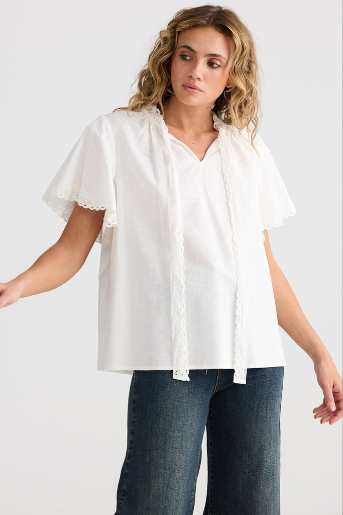 Woman wearing a white blouse and blue jeans on a plain background