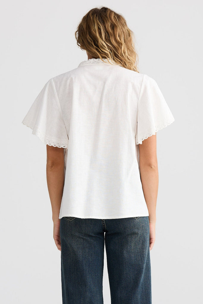 Person wearing a white shirt and blue jeans on a plain background