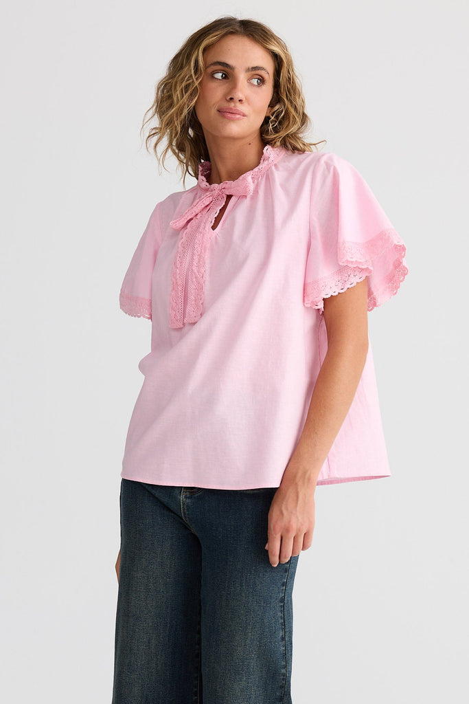 Woman wearing a pink blouse and blue jeans on a white background