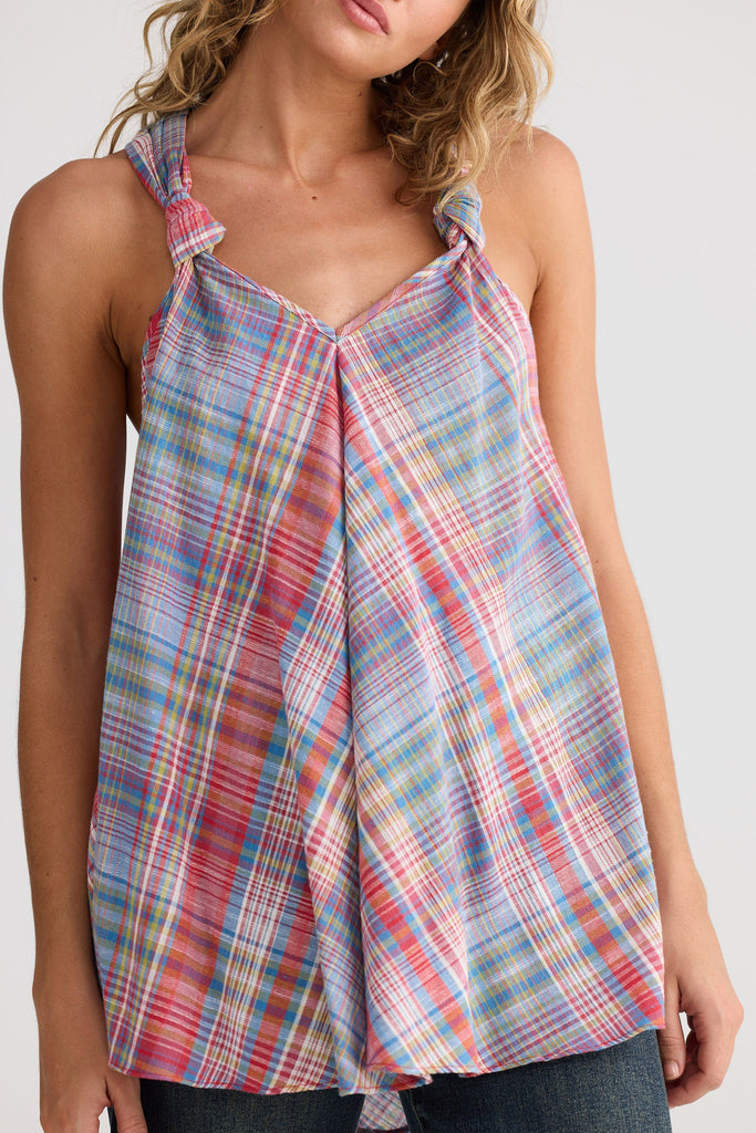 Woman wearing a colorful plaid tank top against a white background