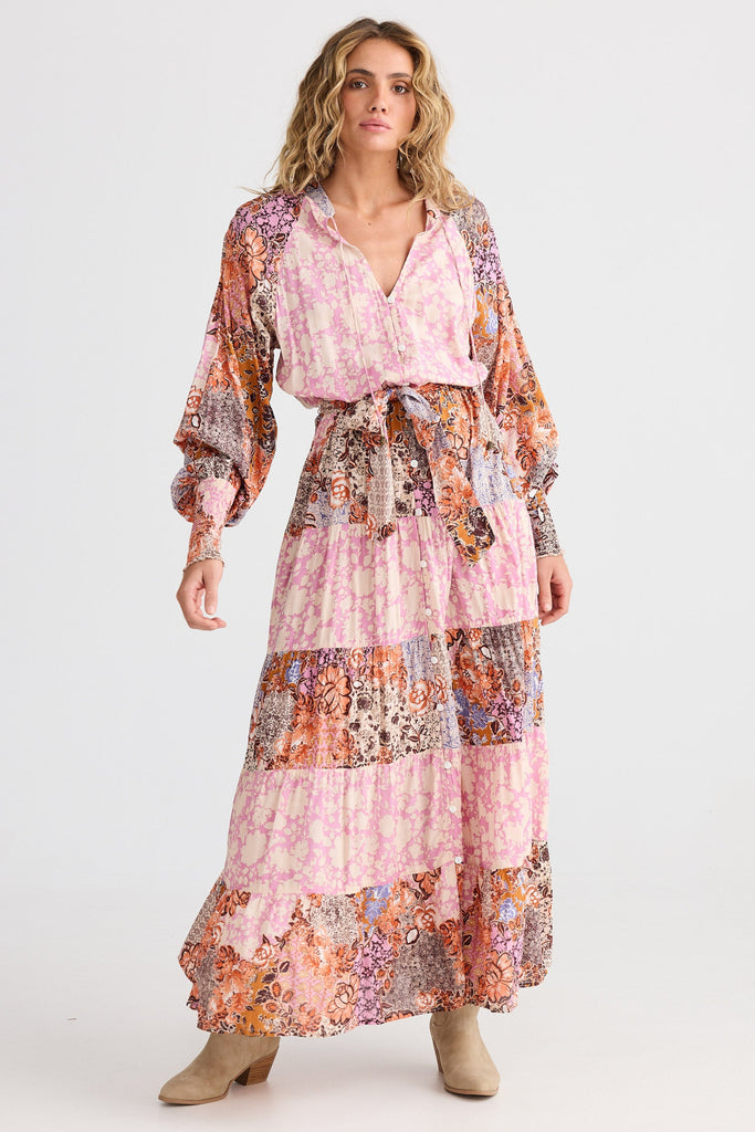 Woman wearing a long, patterned dress on a white background