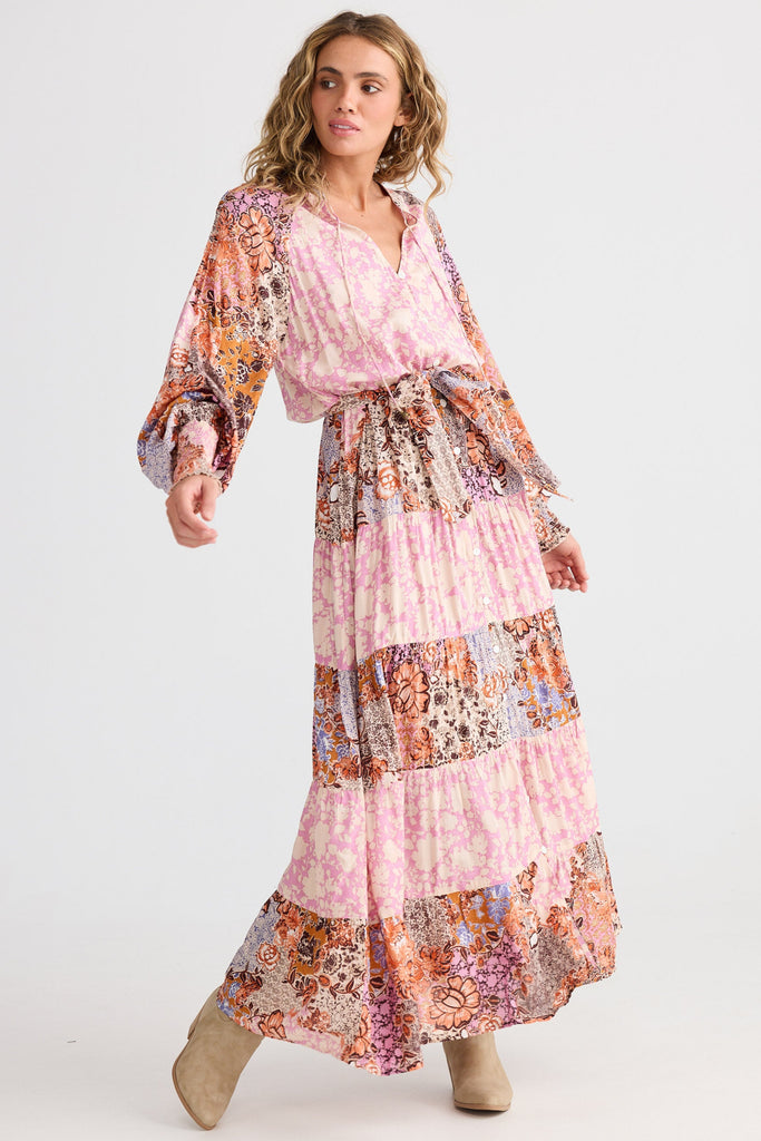 Woman wearing a long, floral-patterned dress on a white background