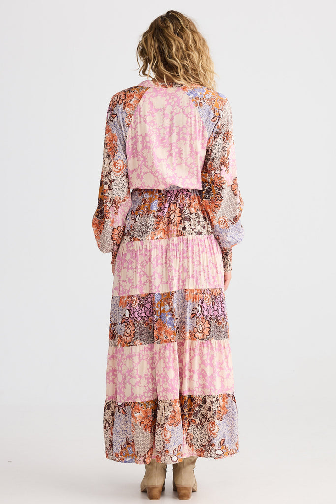 Woman wearing a long, floral-patterned dress on a white background