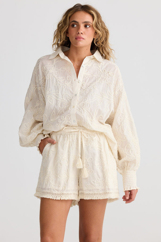 Woman wearing a white lace outfit on a plain background