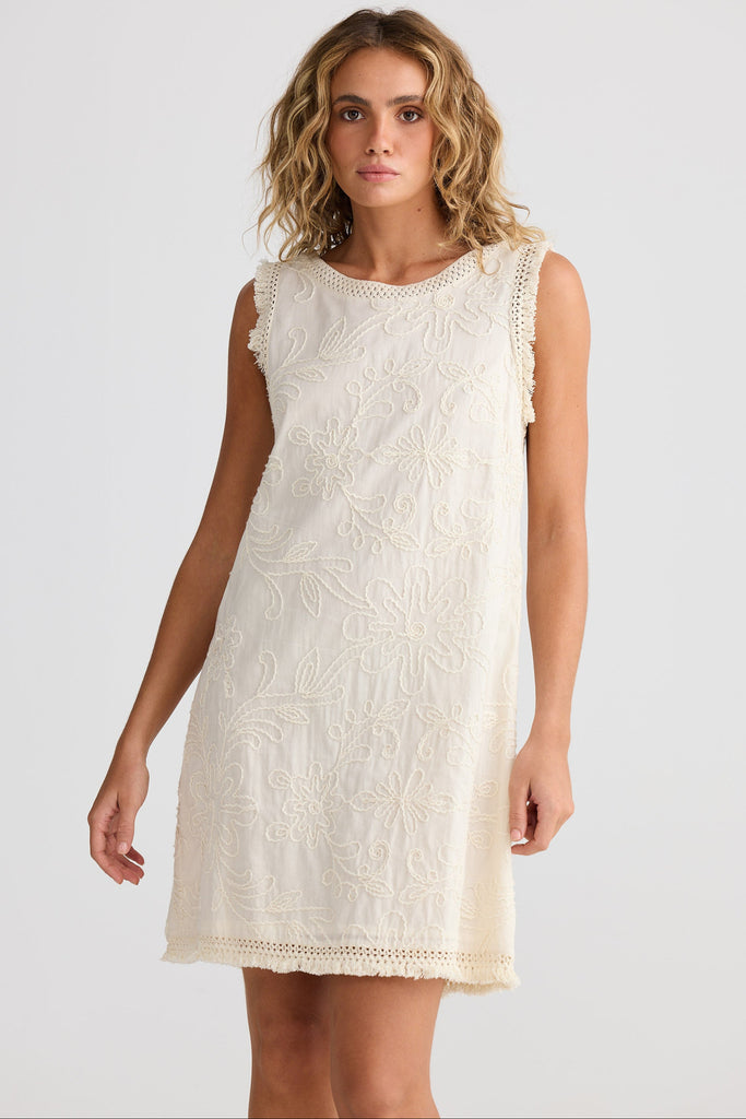 Woman wearing a white lace dress against a plain background