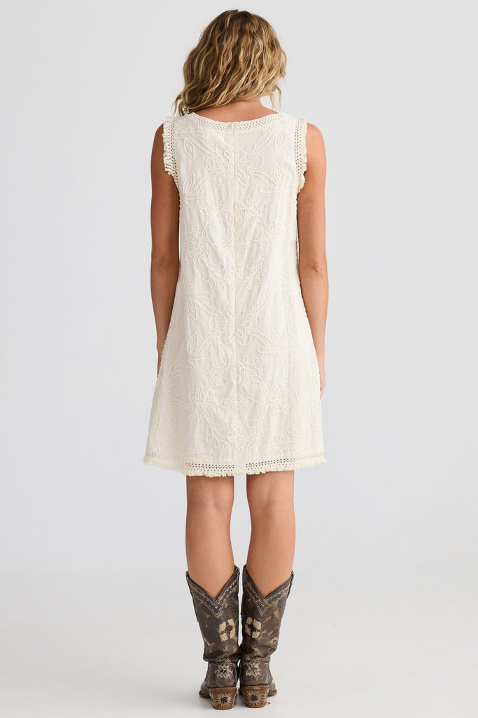 Woman wearing a white sleeveless dress and cowboy boots on a white background