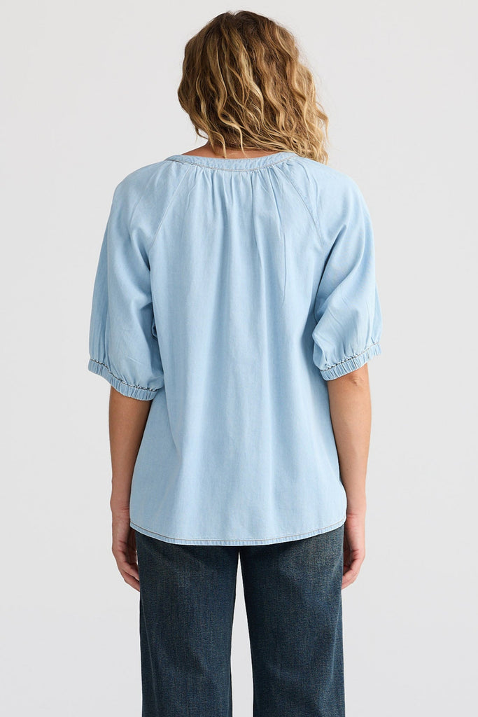 Person wearing a light blue shirt and dark blue jeans on a white background