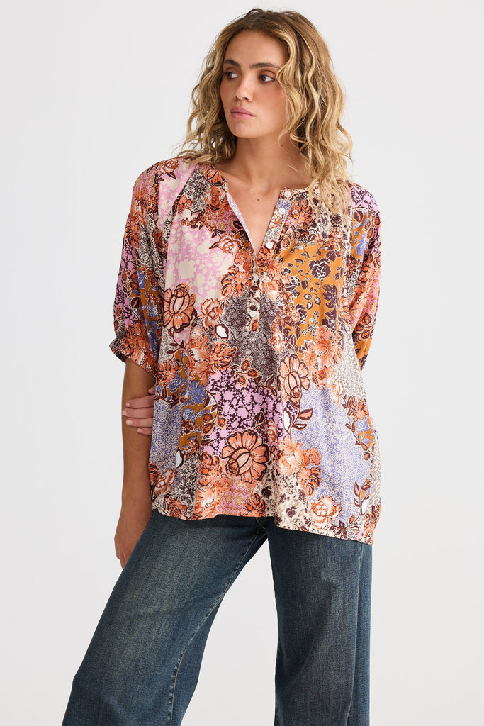 Woman wearing a floral blouse and jeans on a white background