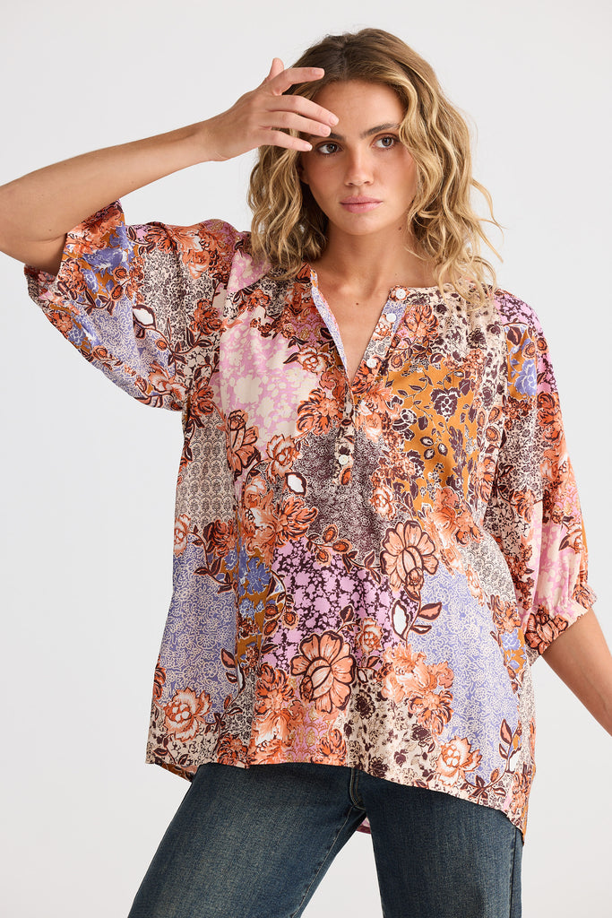 Woman wearing a patterned blouse with a plain background