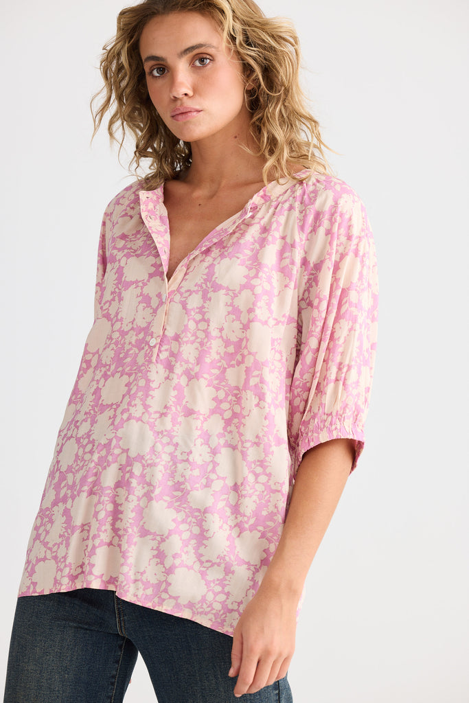 Woman wearing a pink floral blouse against a white background