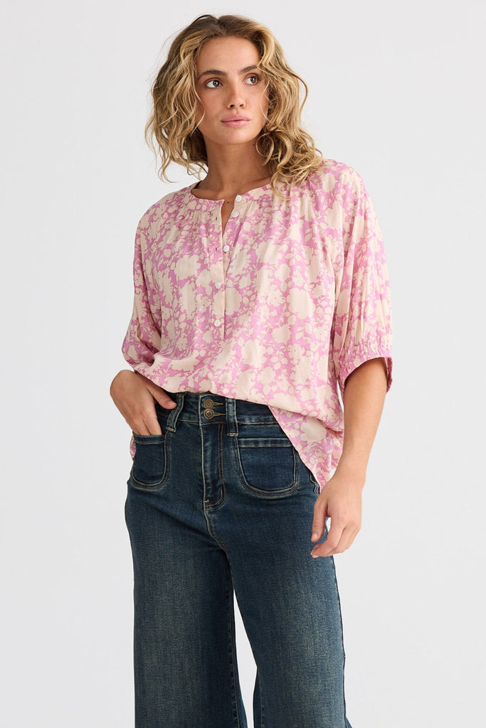 Woman wearing a pink blouse and blue jeans on a white background