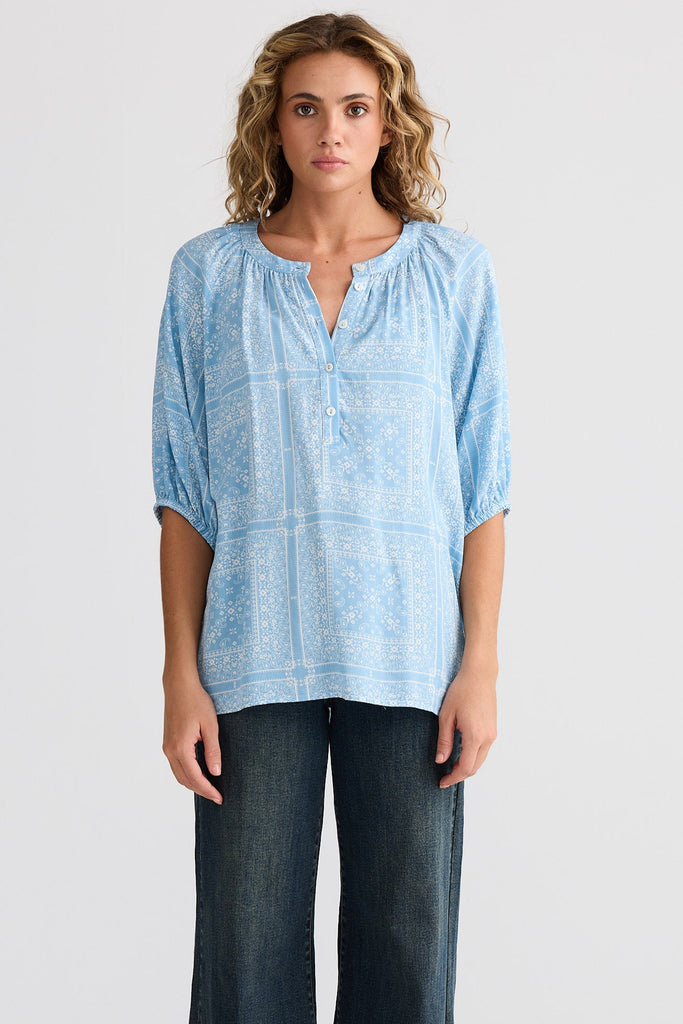 Woman wearing a light blue blouse and dark jeans on a white background