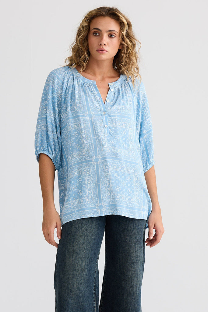 Woman wearing a light blue blouse and dark blue jeans on a white background