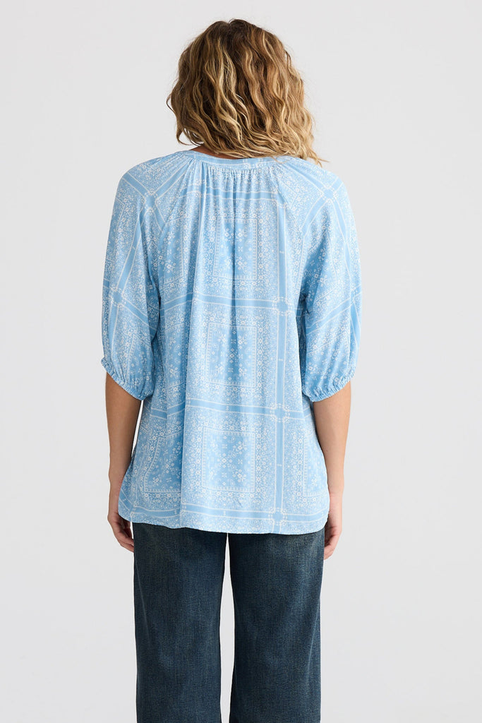Person wearing a light blue blouse and dark blue pants on a white background