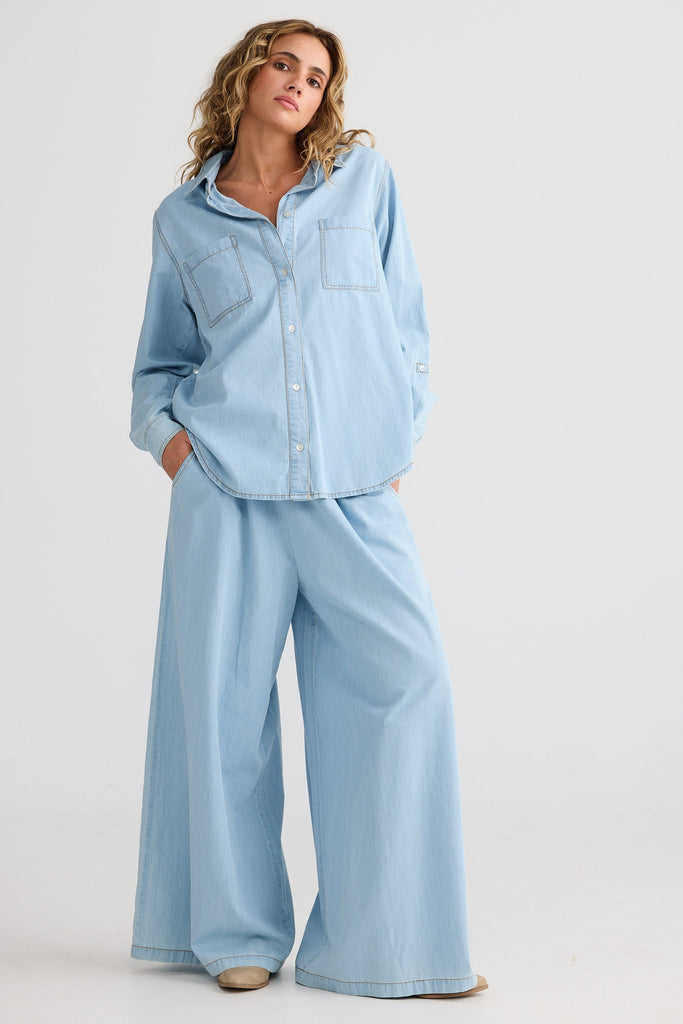 Woman wearing a light blue denim outfit on a white background