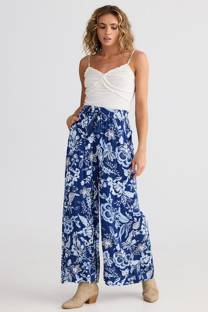 Woman wearing a white top and blue floral pants on a white background