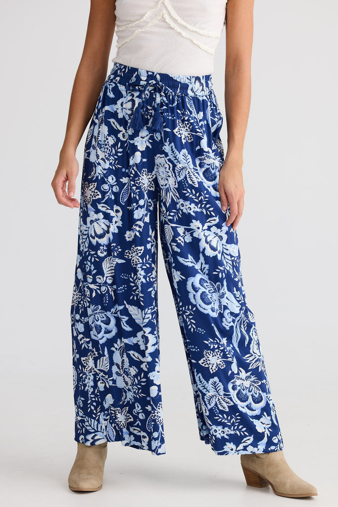 Woman wearing blue floral pants on a white background