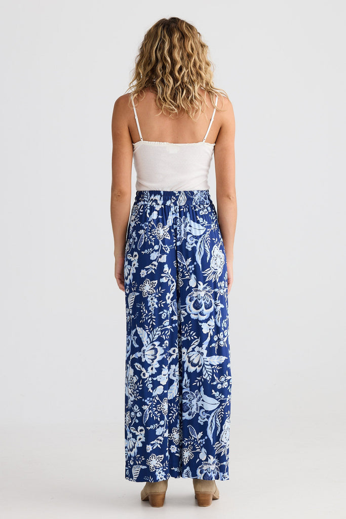 Woman wearing a white top and blue floral pants on a white background