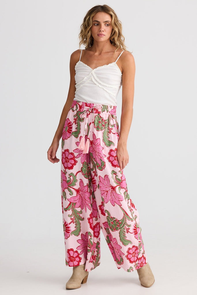 Woman wearing a white top and pink floral pants on a white background