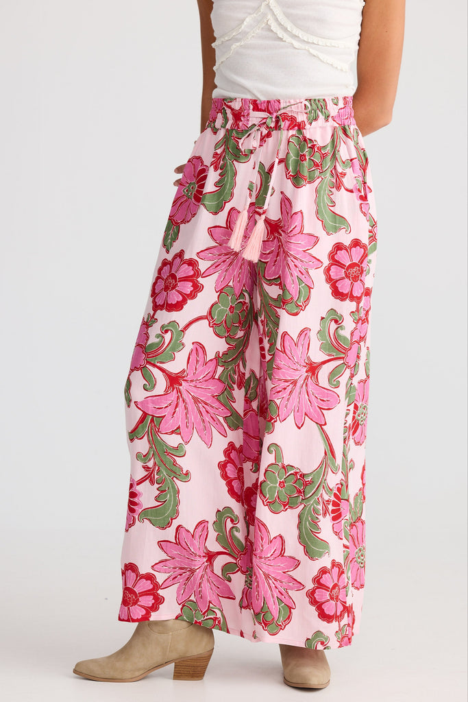 Person wearing a white top and pink floral pants on a white background