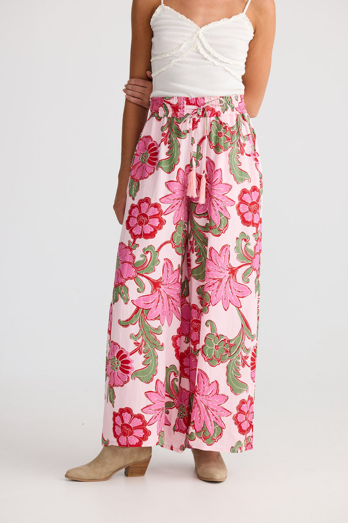 Person wearing a white top and pink floral pants on a plain background