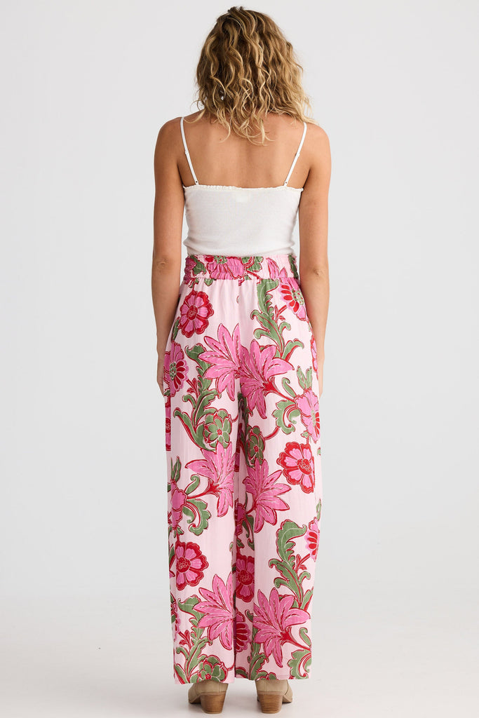 Woman wearing a white top and pink floral pants on a white background