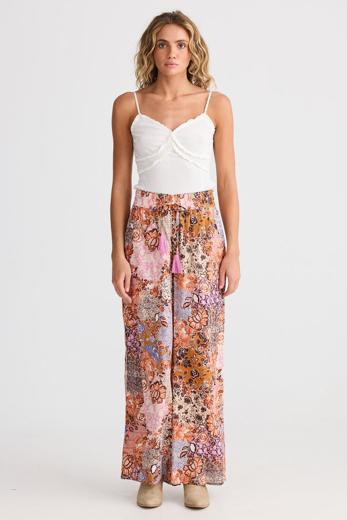 Woman wearing a white top and floral pants on a white background
