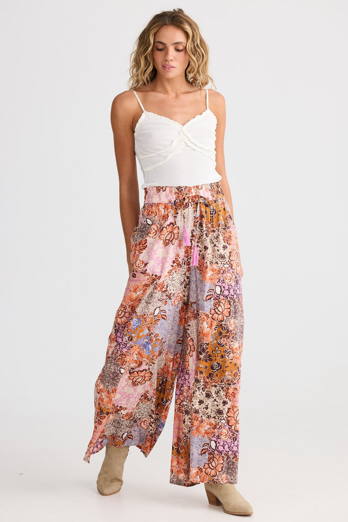 Woman wearing a white top and colorful floral pants on a white background