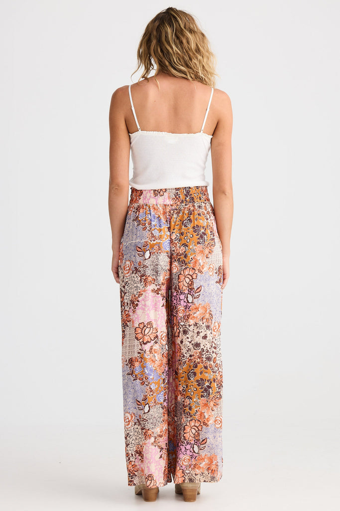 Woman wearing a white top and colorful floral pants on a white background