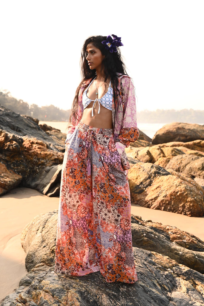 Woman in a colorful top and pant set on rocks by the water