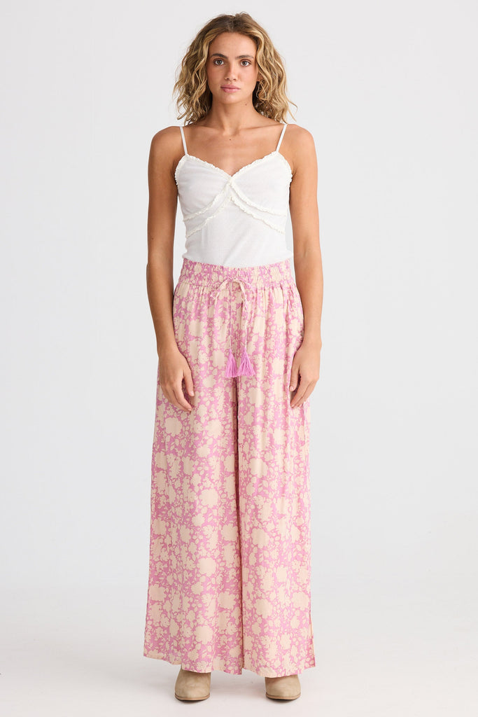 Woman wearing a white top and pink floral skirt on a white background