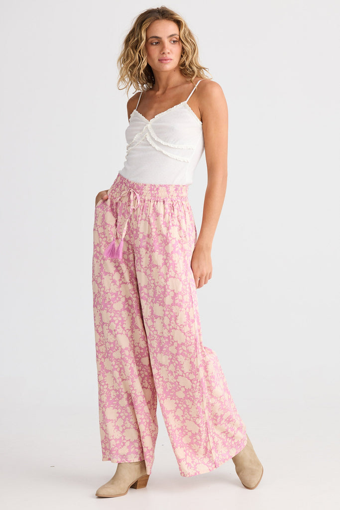 Woman wearing a white top and pink floral pants on a white background