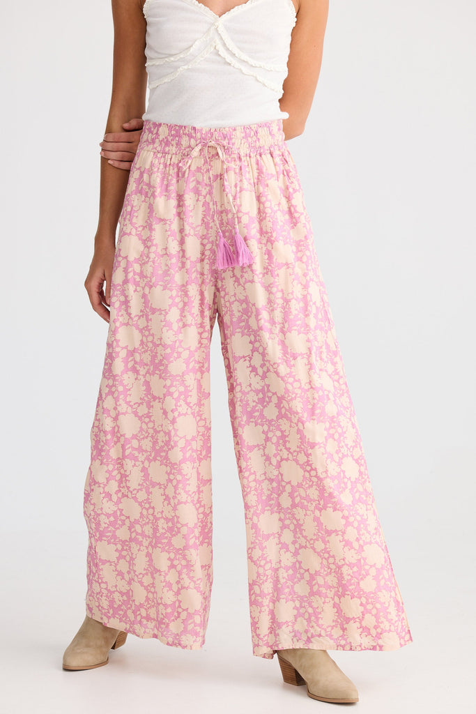 Person wearing a white top and pink floral pants on a white background