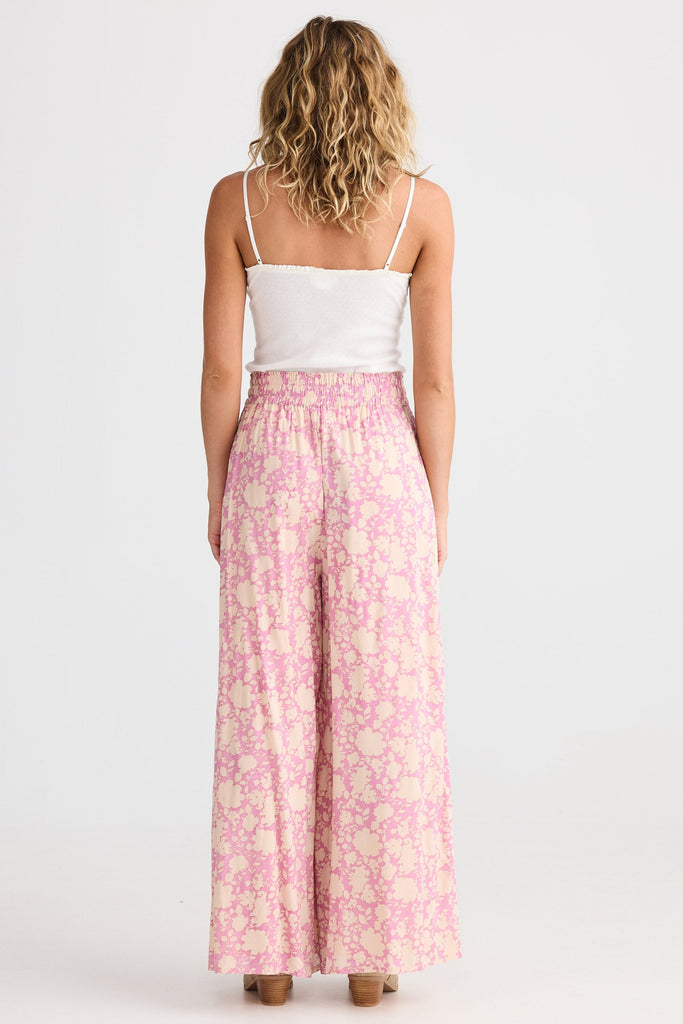 Woman wearing a white top and pink floral pants on a white background